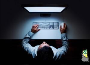 Man sitting at glowing computer screen in darkness